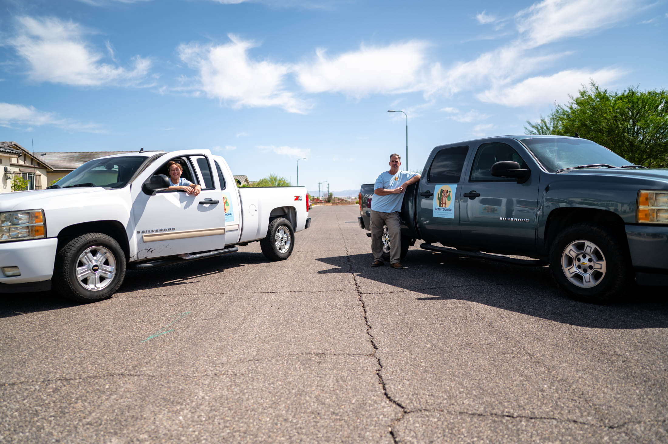 Two men talking near their pickup trucks on a sunny day.